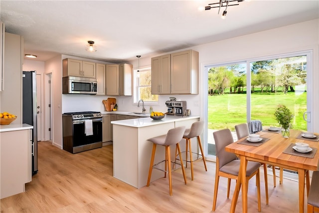kitchen featuring appliances with stainless steel finishes, gray cabinets, light wood finished floors, and a peninsula