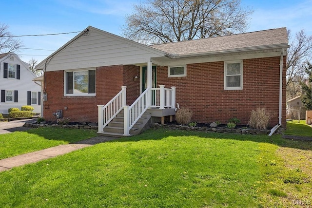 view of front of house featuring roof with shingles, a front yard, and brick siding