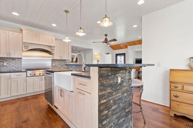 kitchen with a breakfast bar, dark wood-type flooring, wooden ceiling, a sink, and stainless steel appliances