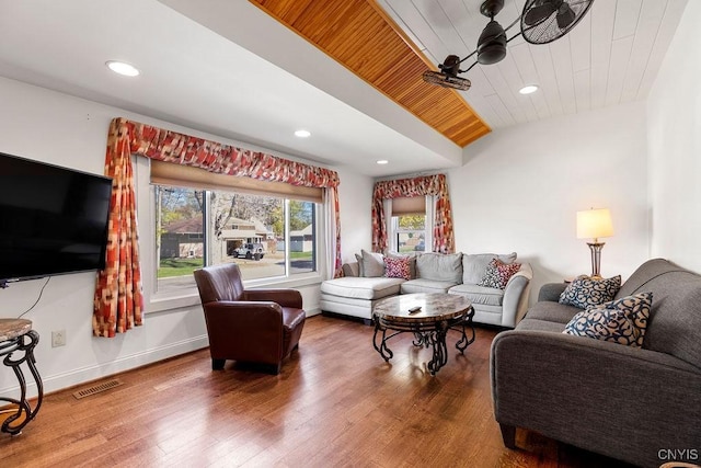 living area featuring visible vents, plenty of natural light, wood finished floors, and vaulted ceiling