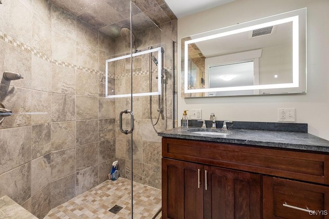 full bath featuring vanity, a stall shower, and visible vents