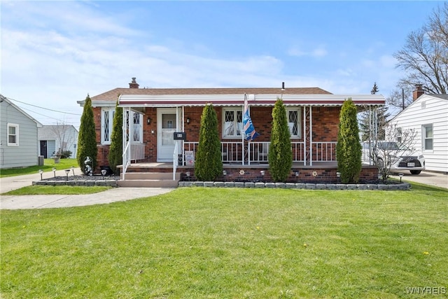 view of front facade featuring covered porch, a chimney, a front yard, and brick siding