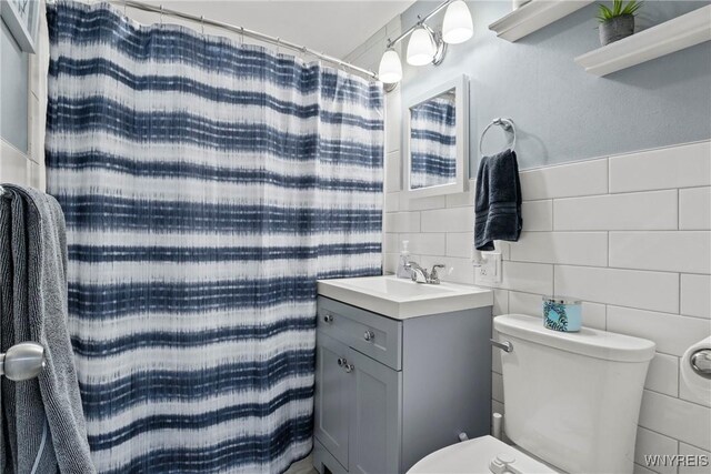 full bathroom featuring vanity, a shower with shower curtain, toilet, and tile walls