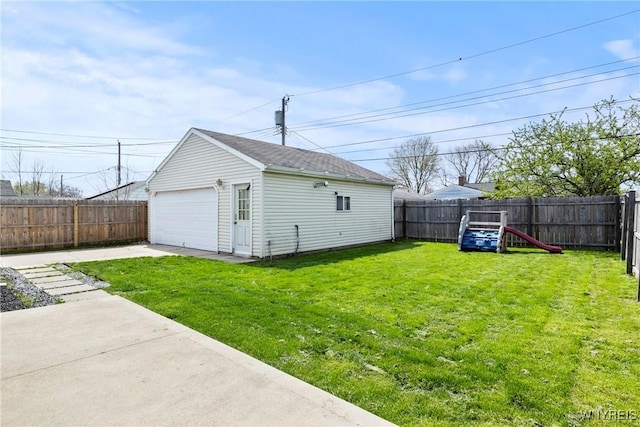 view of yard featuring a detached garage, an outbuilding, and a fenced backyard