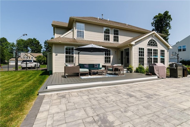 rear view of property with outdoor lounge area, fence, a deck, a patio, and a lawn
