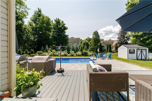 outdoor pool featuring a storage unit, a patio, a wooden deck, an outdoor structure, and a grill