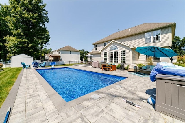 view of swimming pool with fence, an outdoor hangout area, a fenced in pool, a patio area, and a storage shed