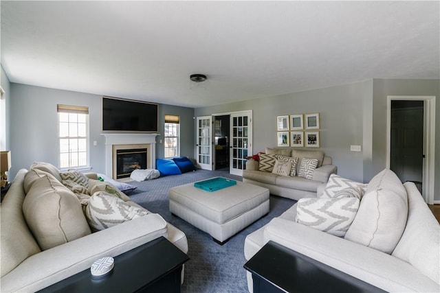 living room with a glass covered fireplace, a wealth of natural light, and dark colored carpet