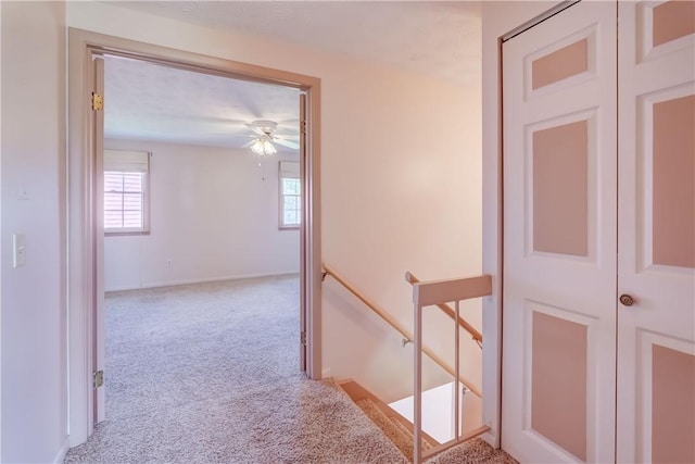 corridor featuring baseboards, carpet flooring, and an upstairs landing