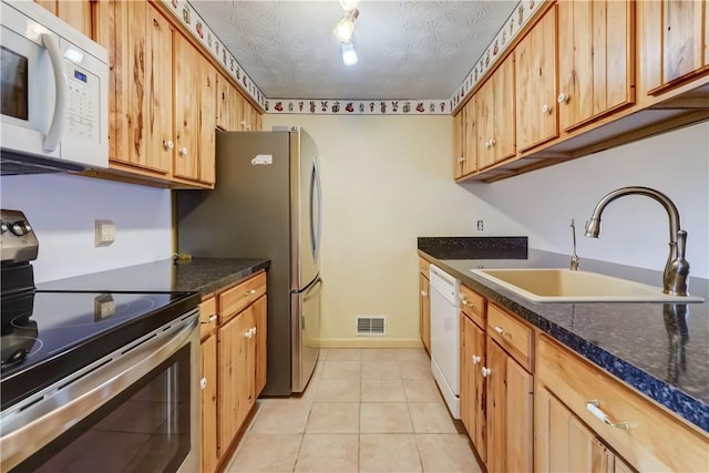 kitchen with light tile patterned flooring, a sink, white appliances, baseboards, and visible vents