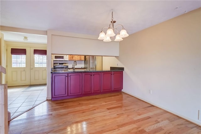 kitchen featuring a sink, appliances with stainless steel finishes, dark countertops, and an inviting chandelier