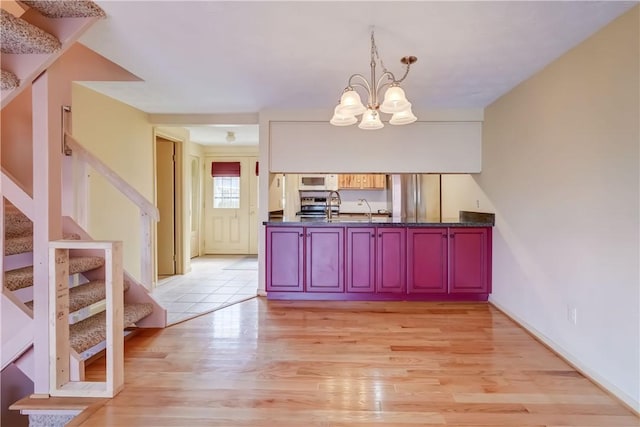 kitchen featuring pendant lighting, dark countertops, light wood finished floors, appliances with stainless steel finishes, and a notable chandelier