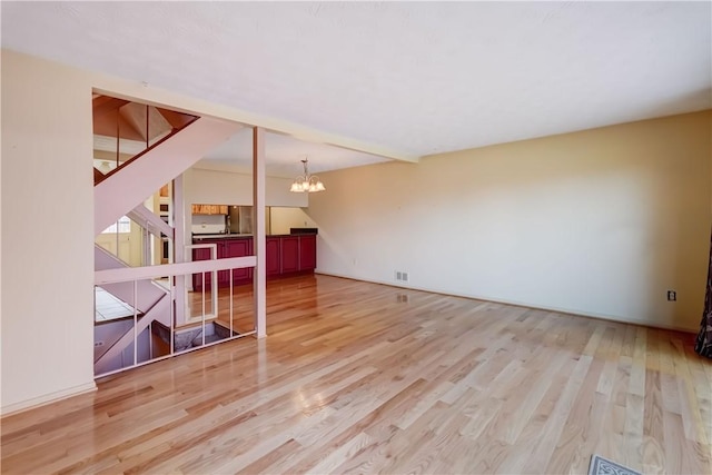unfurnished living room featuring stairs, wood finished floors, and a chandelier