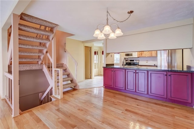 kitchen with a notable chandelier, dark countertops, appliances with stainless steel finishes, and light wood-style floors