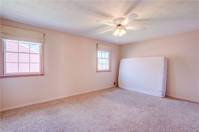 unfurnished room with carpet floors, baseboards, and a ceiling fan