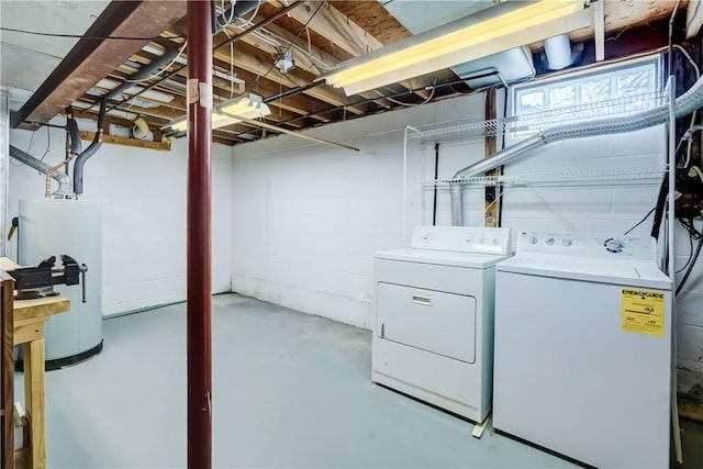 below grade area featuring water heater, concrete block wall, and washing machine and clothes dryer