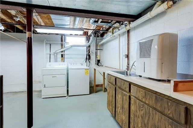 unfinished basement with a sink, concrete block wall, and independent washer and dryer