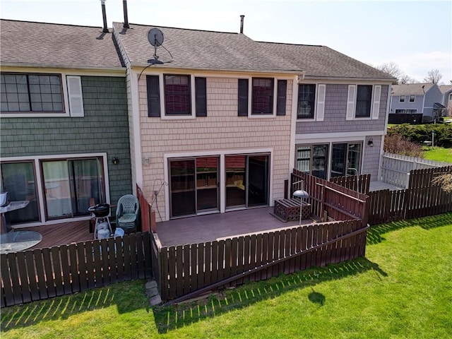 rear view of property with a lawn, a shingled roof, fence, and a deck
