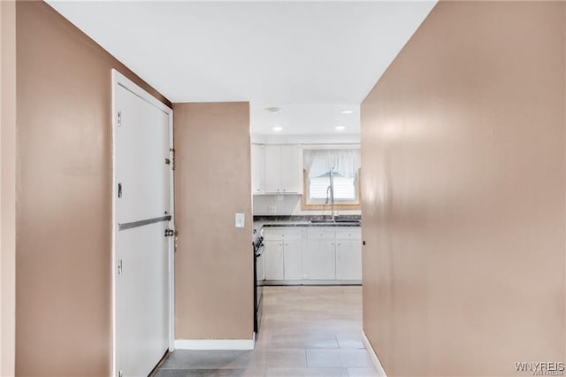 hallway with baseboards, a sink, and recessed lighting