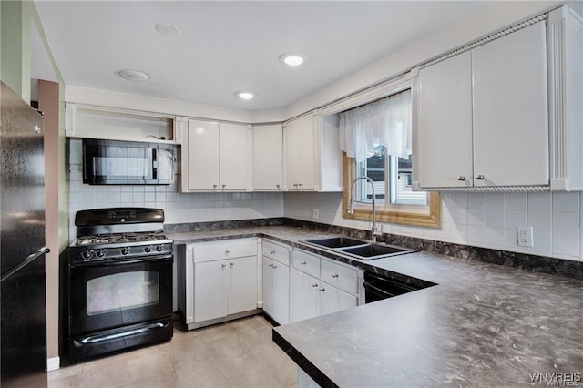 kitchen featuring white cabinets, dark countertops, a sink, decorative backsplash, and black appliances