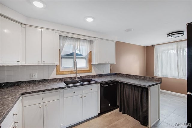 kitchen with black dishwasher, white cabinets, dark countertops, and a sink