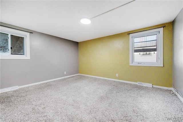 carpeted spare room featuring baseboards and visible vents