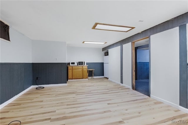 interior space with baseboards, light wood finished floors, and wainscoting