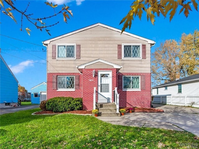 traditional-style home featuring brick siding, fence, a front yard, and entry steps