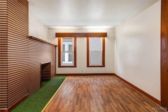 unfurnished living room with baseboards, wood finished floors, and a fireplace