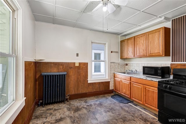 kitchen featuring brown cabinets, radiator, black appliances, and light countertops