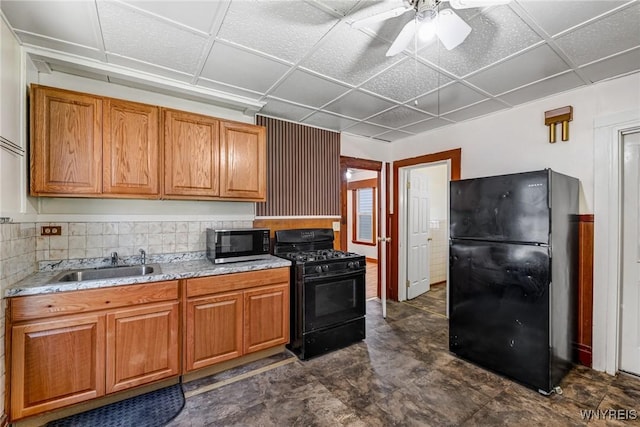 kitchen featuring brown cabinetry, a sink, a ceiling fan, and black appliances