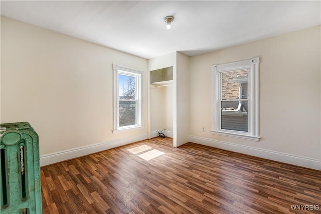 spare room with baseboards and wood finished floors