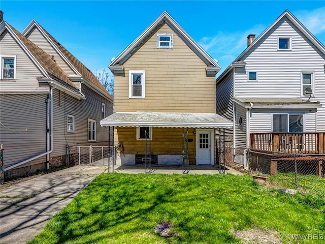 back of house with a wooden deck, fence, a patio, a gate, and a lawn