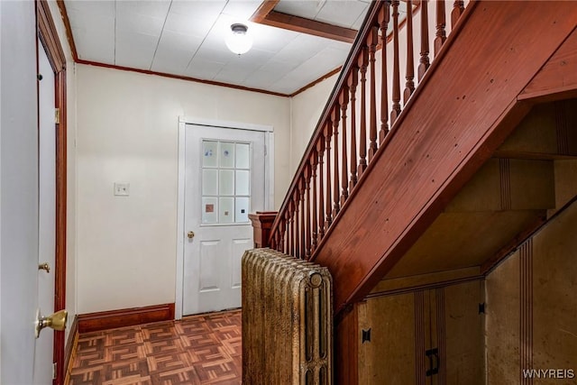 entrance foyer featuring crown molding, baseboards, and stairway