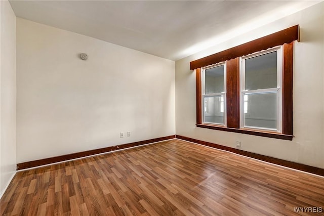 spare room with baseboards and wood finished floors