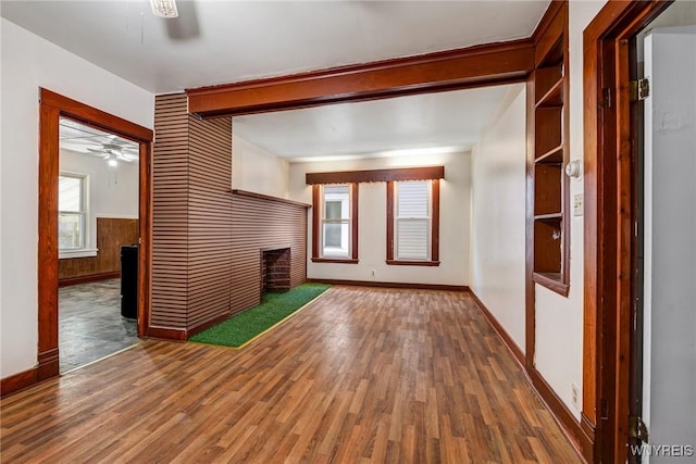 unfurnished living room featuring baseboards, a ceiling fan, a multi sided fireplace, and wood finished floors