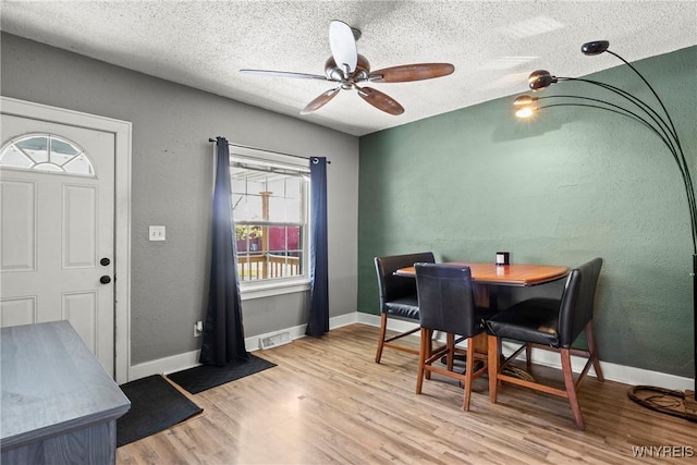 dining space with visible vents, a textured ceiling, ceiling fan, and wood finished floors