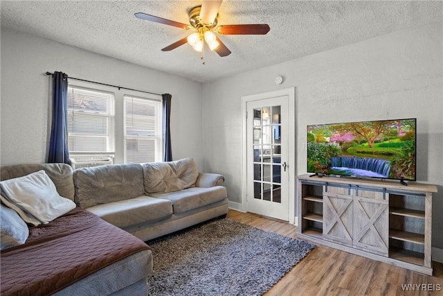 living room with a textured ceiling, ceiling fan, and wood finished floors