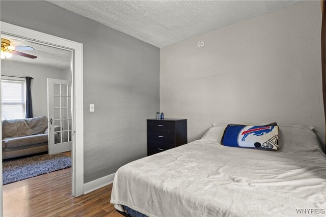bedroom with baseboards, a textured ceiling, and wood finished floors