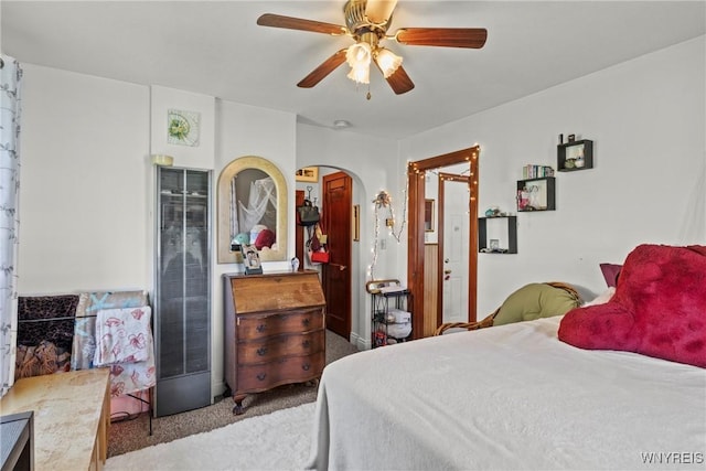 bedroom with carpet floors, arched walkways, a heating unit, and a ceiling fan