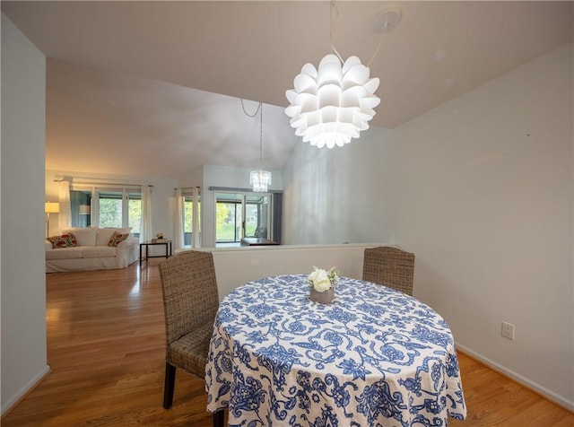 dining area with baseboards, a notable chandelier, wood finished floors, and lofted ceiling