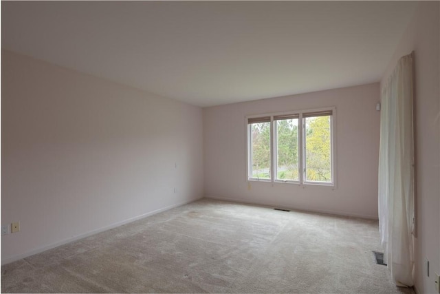spare room with light colored carpet, baseboards, and visible vents