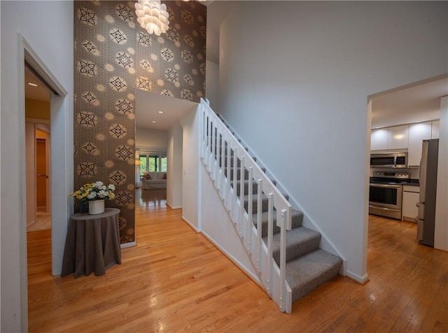 stairs featuring baseboards, a high ceiling, and wood finished floors