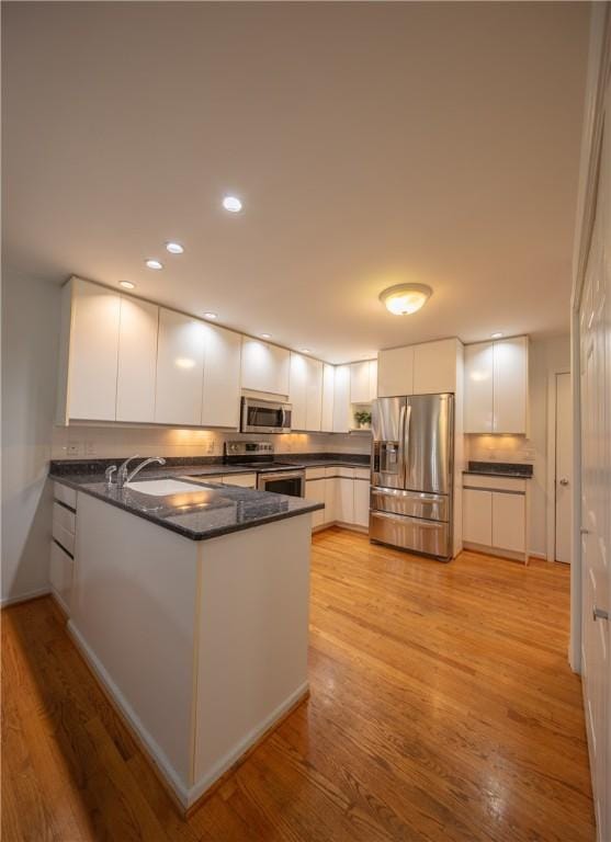 kitchen featuring light wood-style floors, white cabinets, stainless steel appliances, and a peninsula