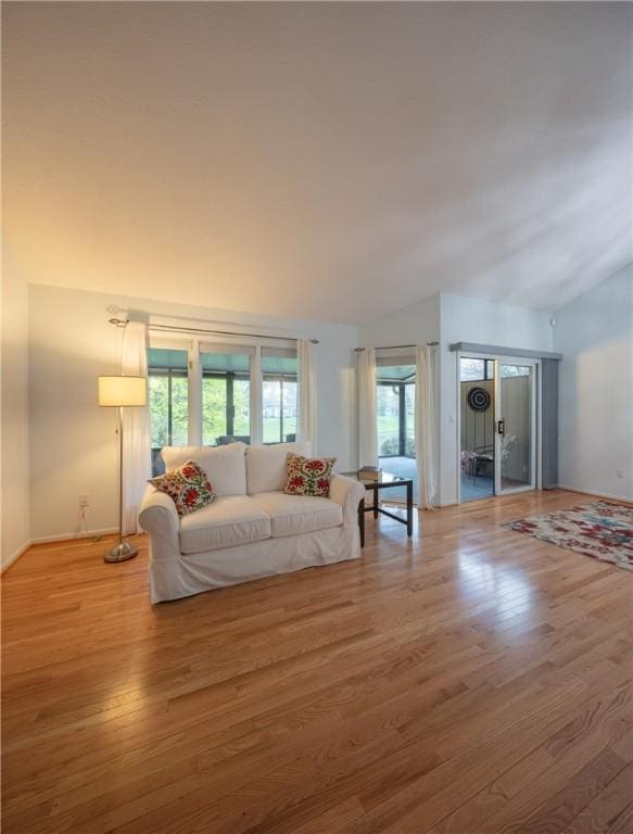 living room with baseboards, vaulted ceiling, and wood finished floors