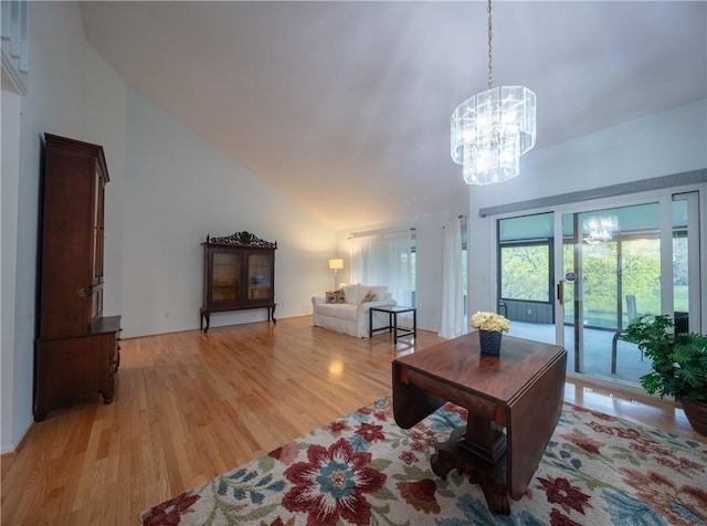 living room featuring light wood finished floors, lofted ceiling, and a notable chandelier