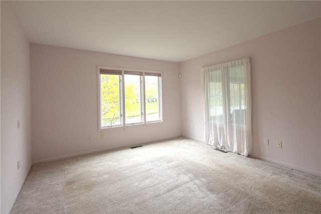 unfurnished room with visible vents, baseboards, and light carpet