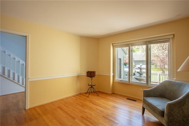 living area featuring visible vents, baseboards, and wood finished floors