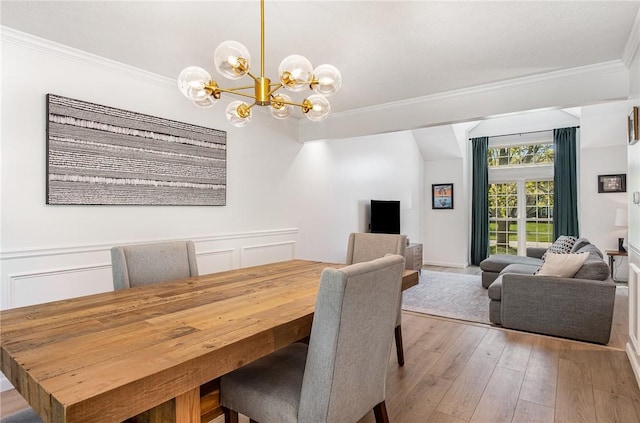 dining area with an inviting chandelier, crown molding, and light wood-style floors