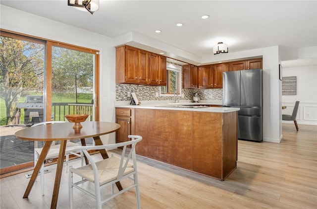 kitchen with light wood-style floors, freestanding refrigerator, a peninsula, and light countertops